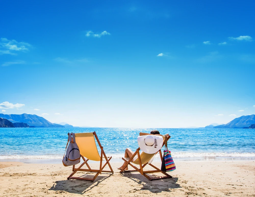 Zwei Liegestühle an einem sonnigen Strand